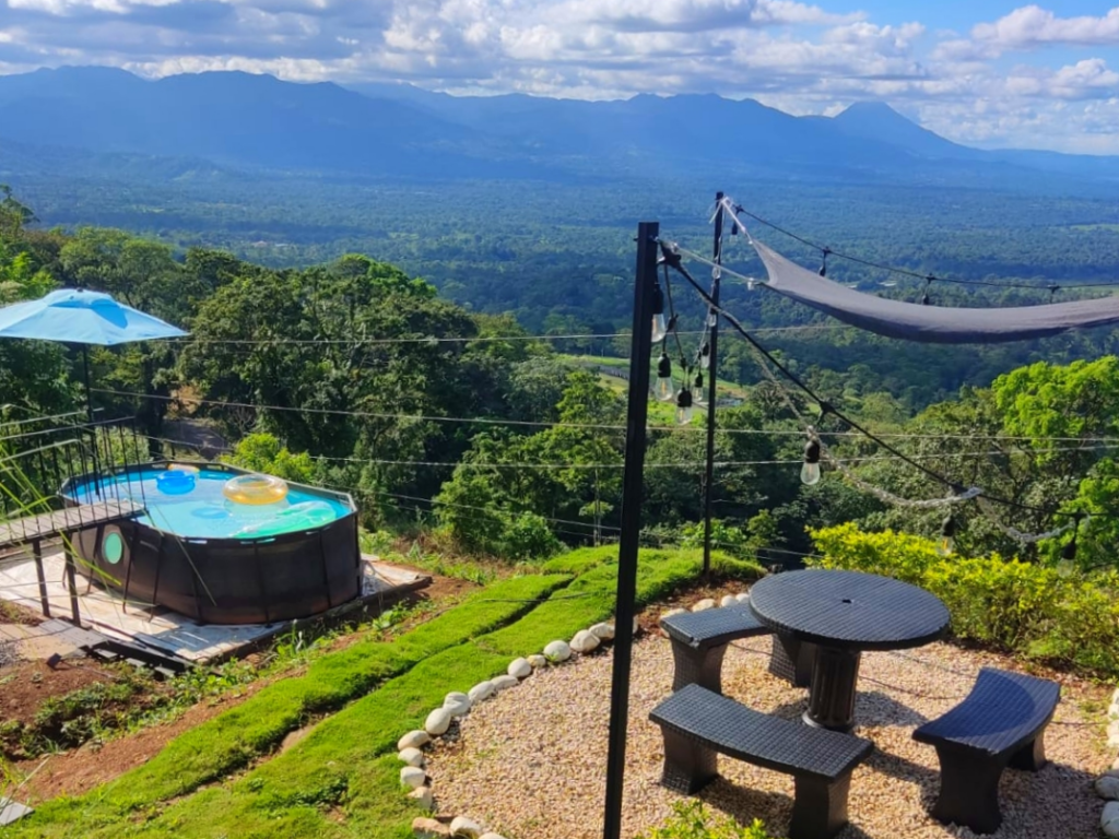 zona de piscina y bancas con vistas a la llanura de San Carlos y el Volcán Arenal en Hygge House